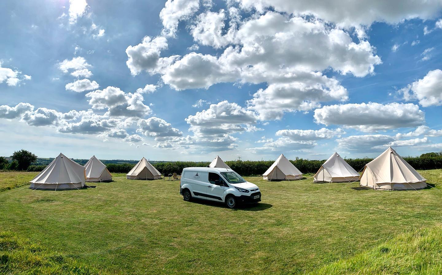 Gecko bell-tent campsite and van beneath summer clouds
