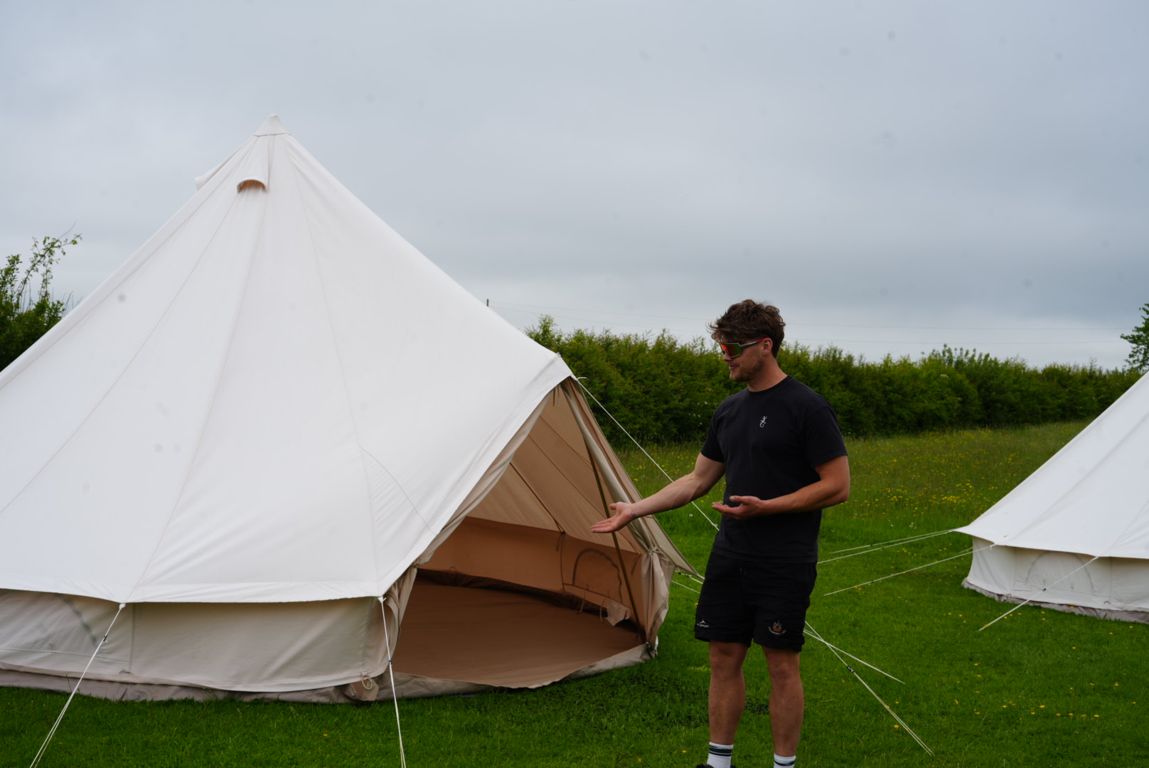 Guest shown into an open bell tent on a grassy field