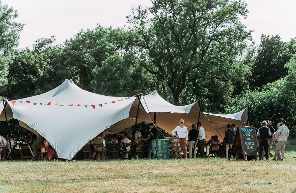 Guests gathered beneath a stretch tent decorated with colourful bunting